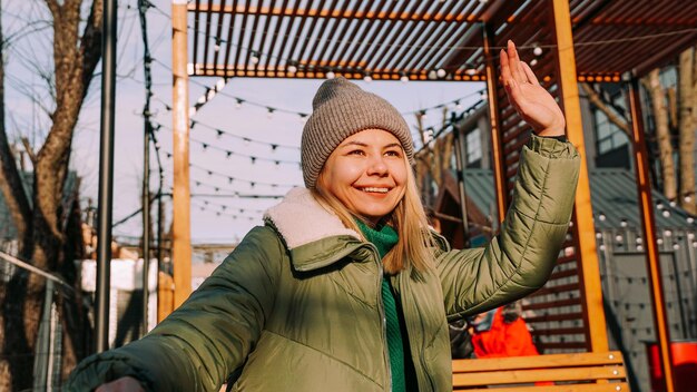 Mujer rubia sonriente sentada en una mesa en un café de la calle del espacio urbano