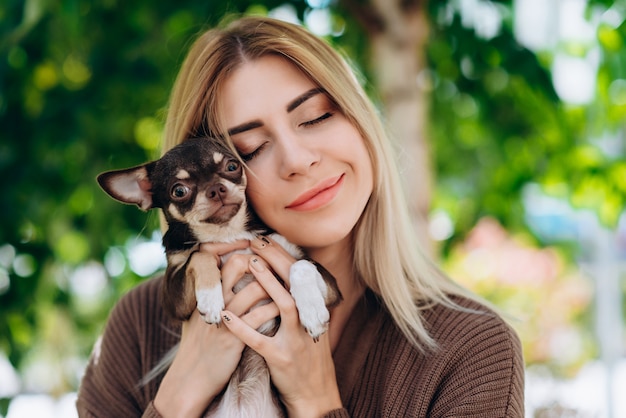 Mujer rubia sosteniendo en sus manos a su mascota y abrazándolo, cerró los ojos