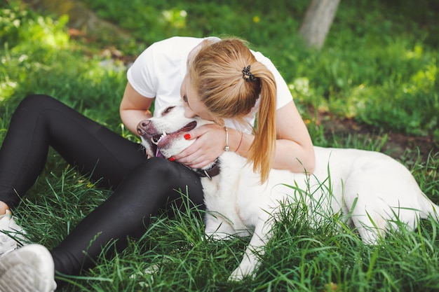 Mujer rubia con su perro perdiguero en el parque niña caucásica jugando con perro en la hierba al aire libre suma ...