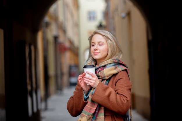 Mujer rubia con taza de café en el casco antiguo