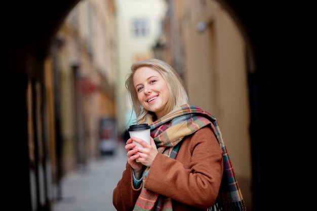 Mujer rubia con taza de café en el casco antiguo