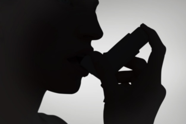 Mujer rubia tomando su inhalador contra viñeta gris