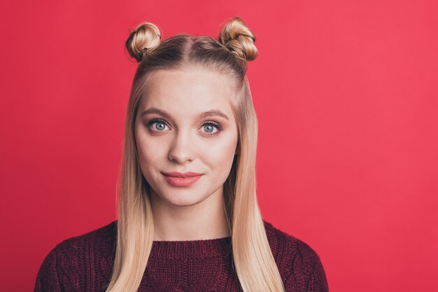 Mujer rubia con top-knots posando contra la pared roja