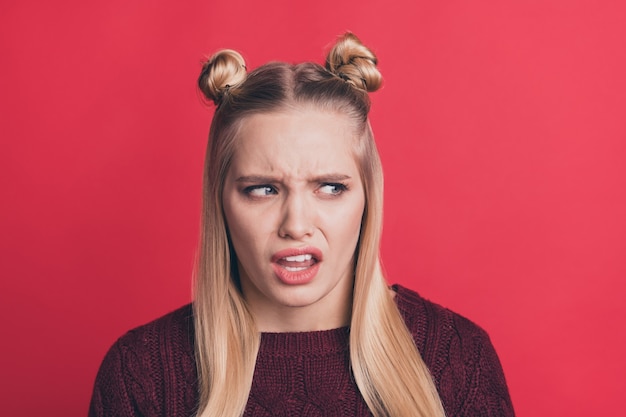 Mujer rubia con top-knots posando contra la pared roja