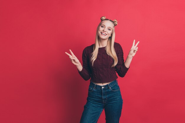 Mujer rubia con top-knots posando contra la pared roja