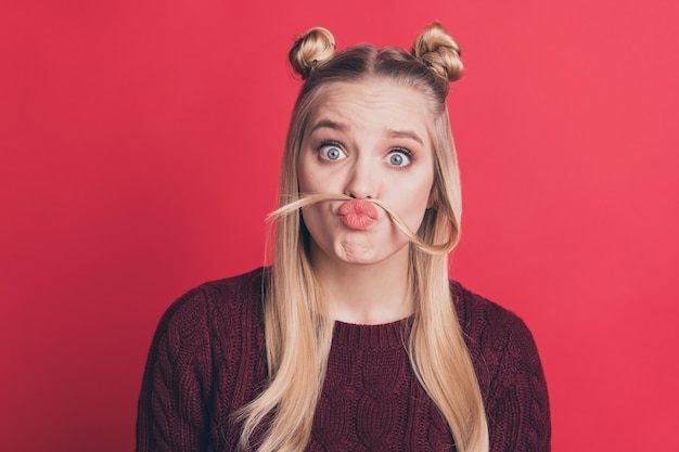 Mujer rubia con top-knots posando contra la pared roja