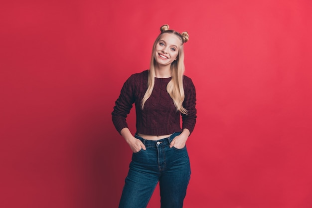 Mujer rubia con top-knots posando contra la pared roja