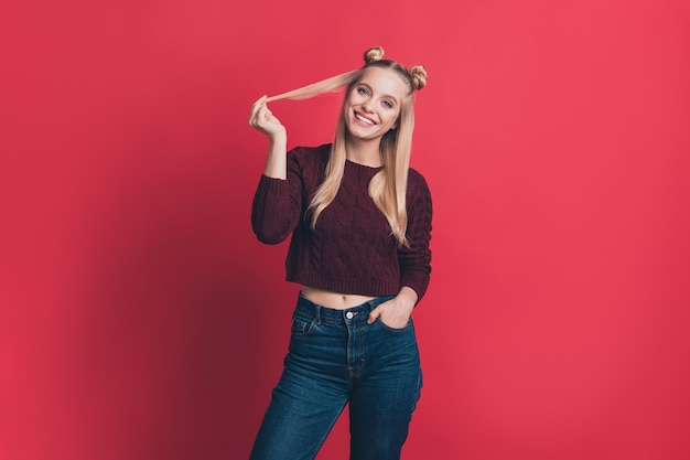 Mujer rubia con top-knots posando contra la pared roja