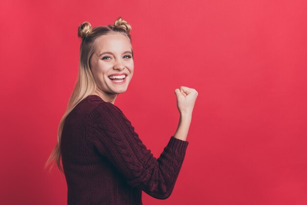 Mujer rubia con top-knots posando contra la pared roja