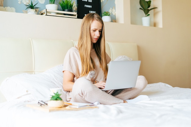 Mujer rubia trabajando en casa con portátil