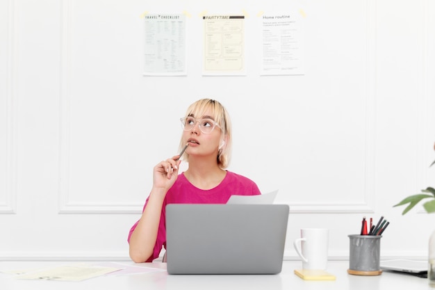 Foto mujer rubia trabajando desde casa en su computadora portátil