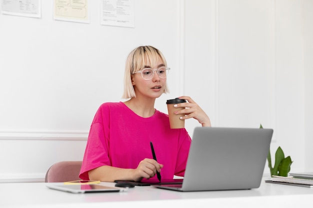 Foto mujer rubia trabajando desde casa en su computadora portátil