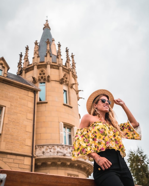 Mujer rubia con un traje vintage amarillo con un sombrero en un castillo