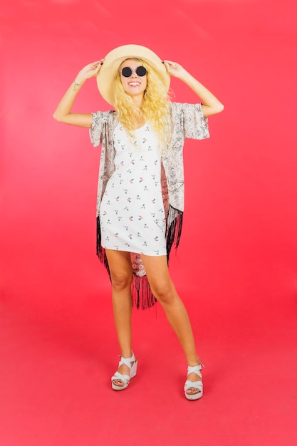 Mujer rubia usa sombrero y gafas de sol en el estudio