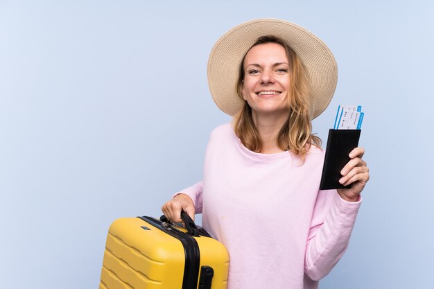 Mujer rubia en vacaciones con maleta y pasaporte