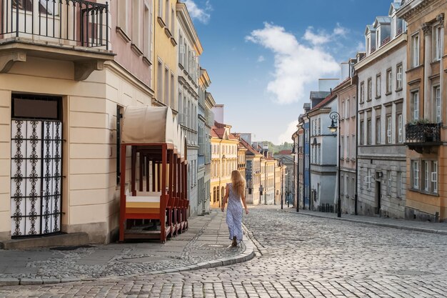 mujer rubia vestida va por la calle en la ciudad vieja
