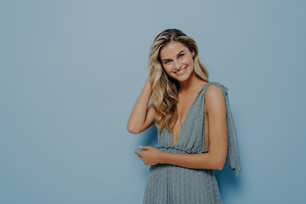 Mujer rubia en vestido azul tocando su cabello