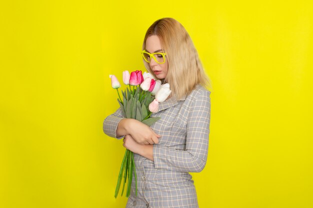 Mujer rubia en vestido a cuadros con ramo de tulipanes