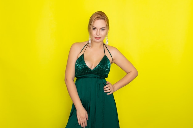 Mujer rubia con vestido de noche verde sobre amarillo