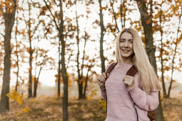 Mujer rubia viajero posando en la parte posterior del bosque de otoño