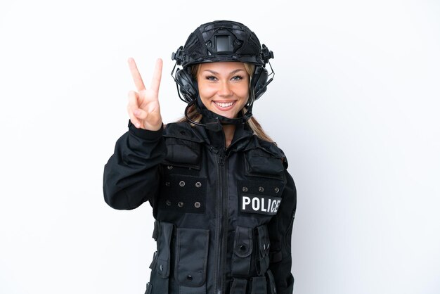 Mujer rusa SWAT aislada sobre fondo blanco sonriendo y mostrando el signo de la victoria