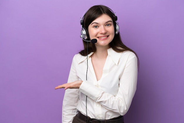 Mujer rusa de telemarketing que trabaja con un auricular aislado en un fondo morado que presenta una idea mientras mira sonriendo hacia