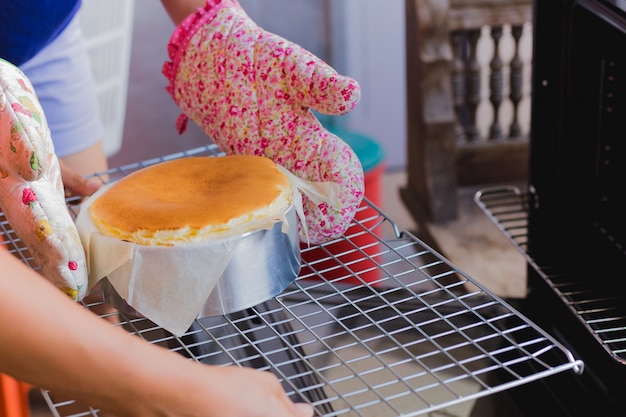 La mujer saca el pastel de queso quemado vasco del horno.