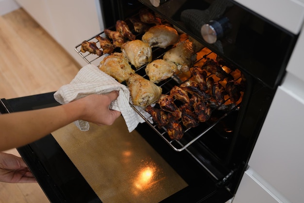 Mujer saca pollo cocido del horno