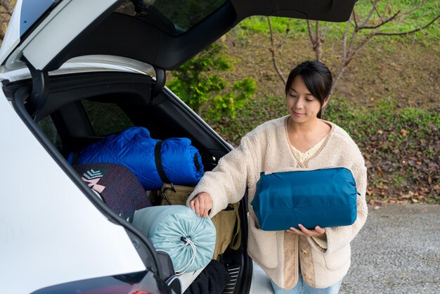 La mujer saca la tienda de campamento del coche