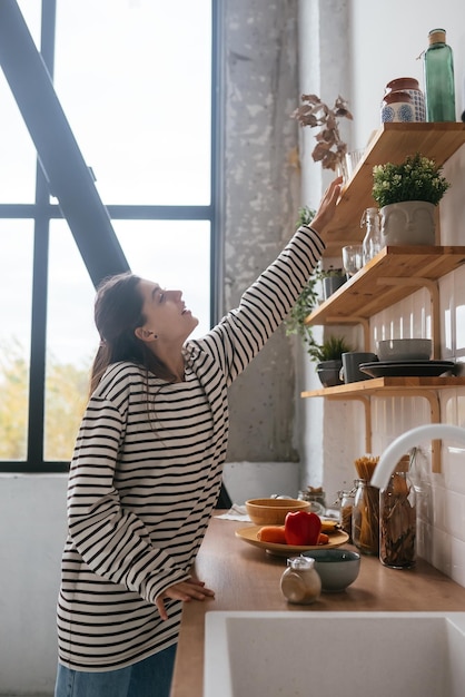 La mujer saca un vaso del estante de la cocina