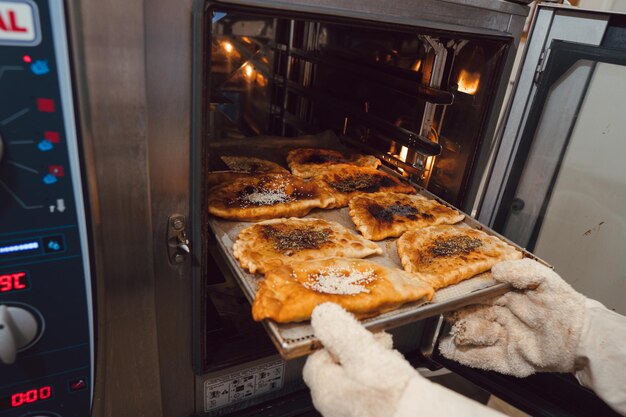 Foto mujer sacando chebureks ucranianos del horno