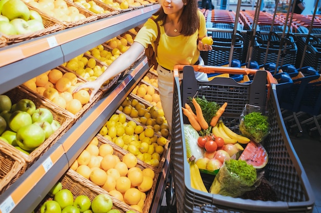 Mujer sacando naranjas del estante de la tienda del supermercado