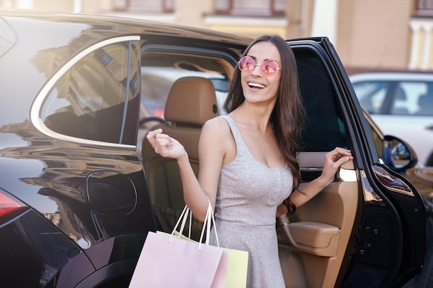 Mujer saliendo del auto con bolsas de compras