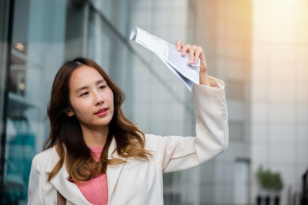 Mujer saliendo del edificio después de terminar el trabajo sombra sol UV con periódico