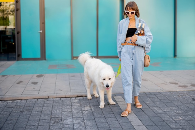 Mujer saliendo con su lindo perro blanco de un supermercado