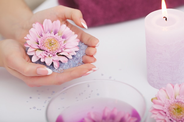 Mujer en salón de belleza con los dedos en el baño de aroma para manos.