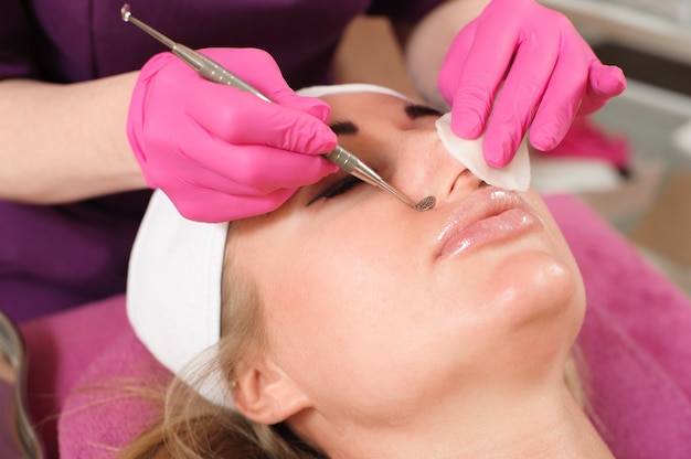 Mujer en el salón de belleza profesional durante un procedimiento de limpieza facial