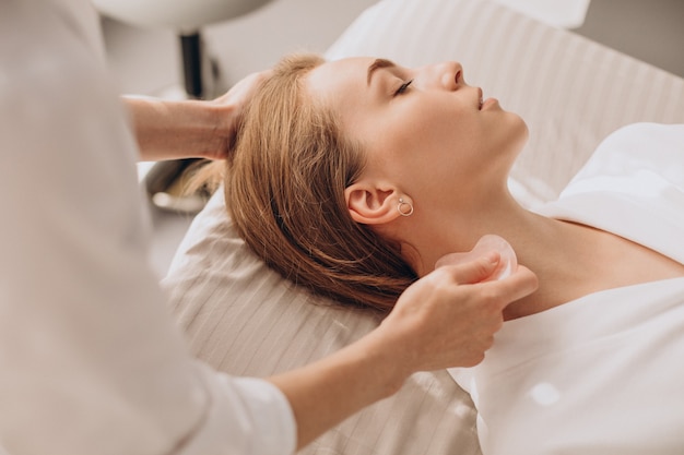 Mujer en el salón haciendo tratamientos de belleza con piedra gua sha