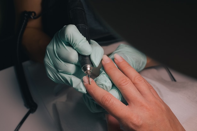 Mujer en un salón de uñas recibiendo manicura por una esteticista. Concepto de tratamiento de belleza.