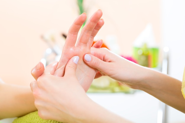 Mujer en un salón de uñas recibiendo una manicura por una esteticista, está recibiendo un masaje de manos