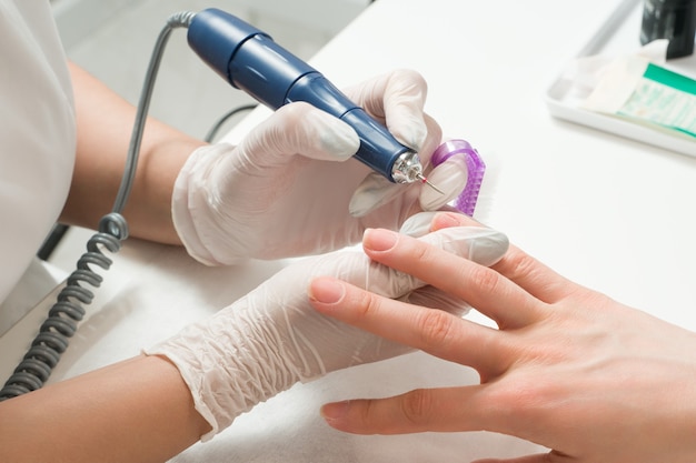 Mujer en un salón de uñas recibiendo una manicura por una esteticista con lima de uñas belleza y cuidado de las manos