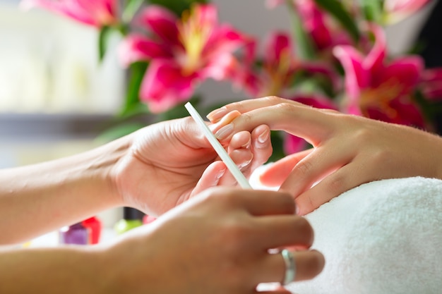 Mujer en salón de uñas recibiendo manicura.