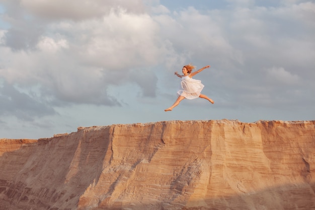 Mujer salta a las dunas de arena al atardecer