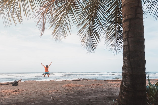 Mujer saltando en la playa contra el cielo.