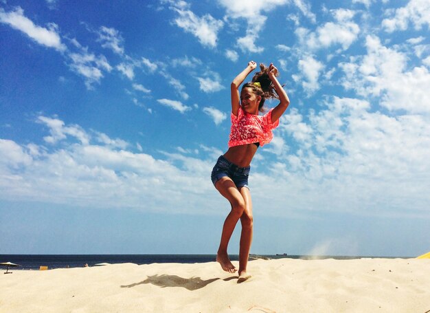 Foto mujer saltando en la playa