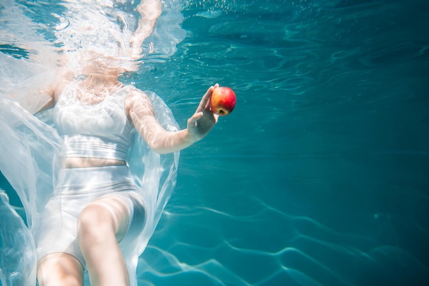 Mujer Salud Chica bajo el agua con una manzana comida sana El concepto de ligereza, frescura y vuelo