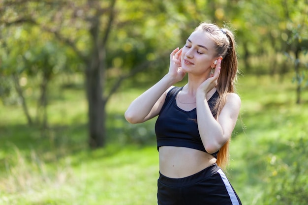 Mujer sana y alegre escuchando música con auriculares en el parque