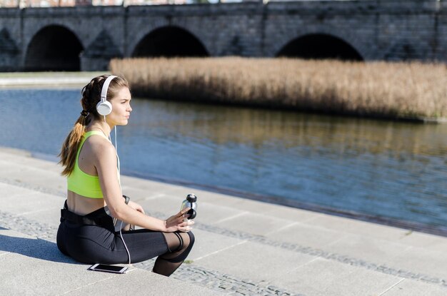 Foto mujer sana descansando y escuchando música con el teléfono móvil mientras hace yoga y ejercicio