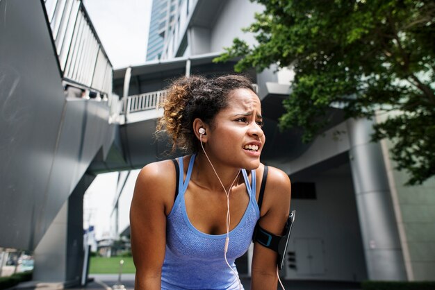 Mujer sana que ejercita mientras que usa tecnología