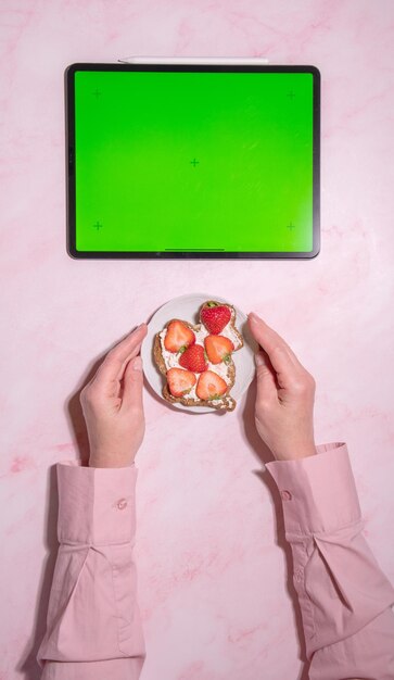 Foto mujer con sándwich de queso suave y fresa cerca de la tableta de pantalla verde